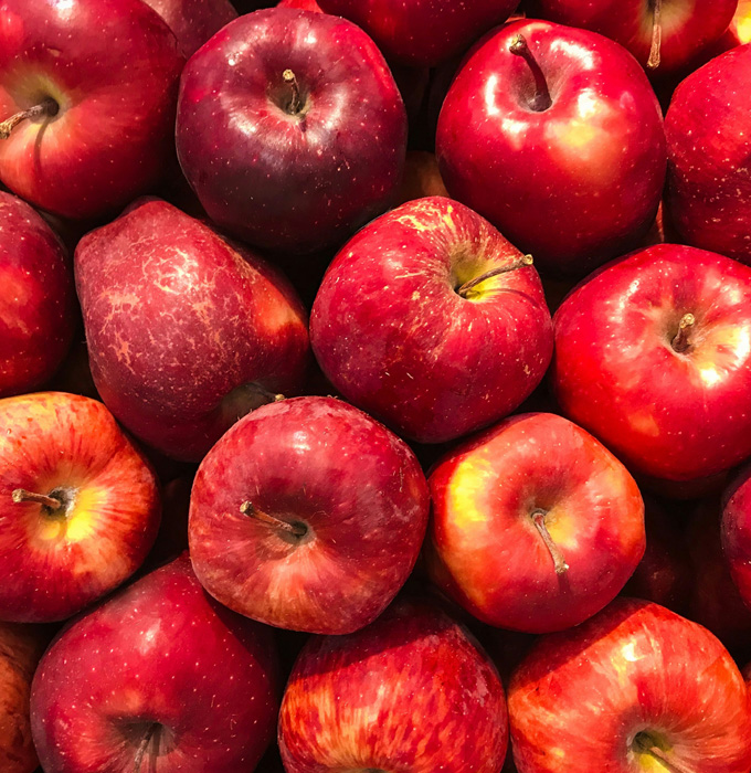 Ein Haufen von roten Äpfeln, verschiedene Größen und Schattierungen. Die Äpfel zeichnen sich durch ihre glänzende Oberfläche und einige kleine Unregelmäßigkeiten aus. Sie sind eng gepackt und bilden eine ansprechende und frische Fruchtansammlung.